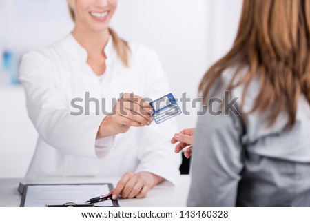 Smiling young doctor giving health card to a patient Royalty-Free Stock Photo #143460328