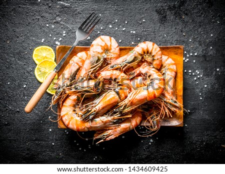 Fragrant shrimps with sliced lemon rings. On black rustic background