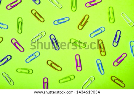 Colorful paper clips on lime green background, copy space. Top view, flat lay. Back to school, business concept. Abstract background