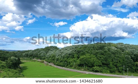 High angle view and wide screen of summer field landscape. Nature green forest hills with blue sky and clouds. Road in the countryside