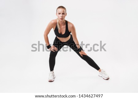 Full length of an attractive young fit sportswoman standing isolated over white background, doing stretching exercises