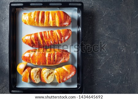 freshly baked yeast dough rolls with Apple filling on a baking pan on a kitchen concrete table, horizontal view from above, flat lay, close-up, copy space