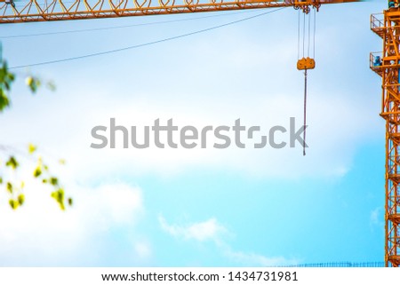 Concept photo of building construction, construction, orange cranes and scaffolding on a bright sunny day against the blue sky.