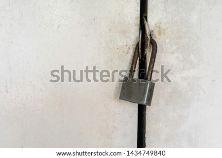 Close-up on rusty silver locked padlock on old dirty white door.
