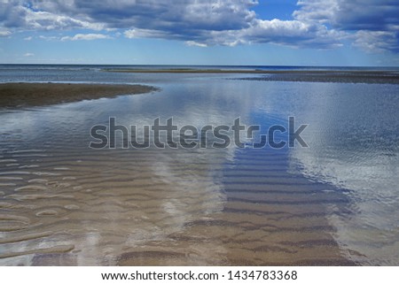Beautiful reflections of clouds in the wet sand and sea on the Cornish beach at Whitsand Bay in early summer, there are 3 miles of stunning coastline for holiday makers to enjoy, Cornwall, UK