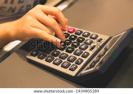 Employees are pressing the calculator, charging customers in the office in the shop for customers, women's hands.