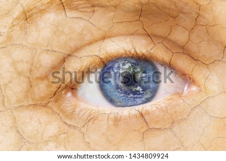Global warming concept. Close up image of woman cracked textured face with iris earth. Creative composite of macro Eye with Earth as Iris. Elements of this image furnished by NASA .