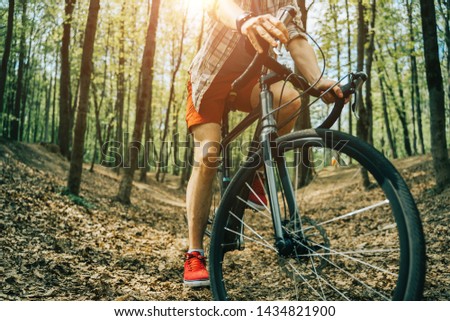 Cropped picture of young man is riding on bicycle.