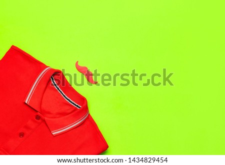 Creative party decoration concept. Red mustache, red polo shirt, props for photo booths, carnival parties on green background top view flat lay copy space. Father's day, Men's clothes accessories