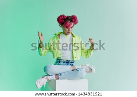 woman with pink hair sitting in the lotus position on the cube