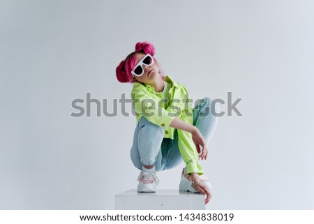stylish woman with pink hair with glasses sits on the cube