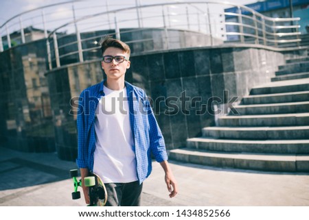 Young boy in glasses posing with a longboard. street photo, life style