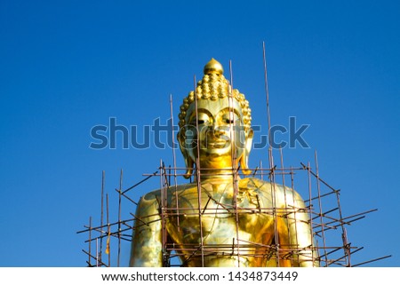A large golden Buddha statue on a blue sky background,Old Buddha image repair