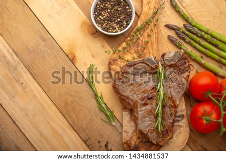 Marbled beef steak on a board with rosemary pepper, spices, and fresh vegetables on a wooden background, restaurant menu, gastronomy, tasty food. Horizontal photo, banner