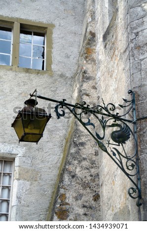 Old street lamp on the background of a stone wall with Windows. Castle in Gruyere, Switzerland