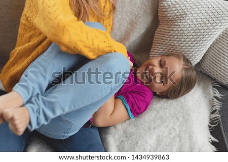 high view of Caucasian mother and daughter having fun on the sofa in a comfortable home