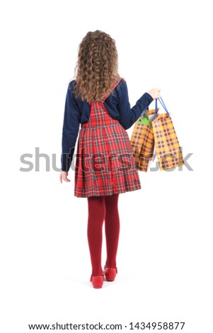 Child with a yellow packaging checkered texture  isolated on white background. Holiday present, shopping. Happy girl with long curly hair. High resolution photo. Full depth of field.