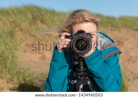 Portrait of a Caucasian blonde female photographer at the beach.
