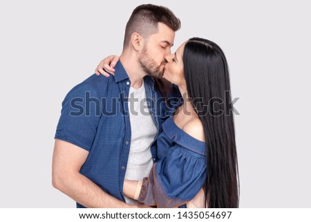 Close-up of young romantic couple is kissing and enjoying the company of each other. isolated wearing denim clothing on ashy-gray background