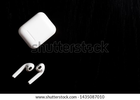 airpods with charging case on black textured background  Royalty-Free Stock Photo #1435087010