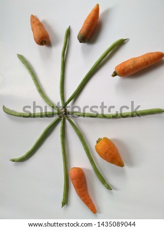 eight beans arranged in a circle and five carrots with a white background