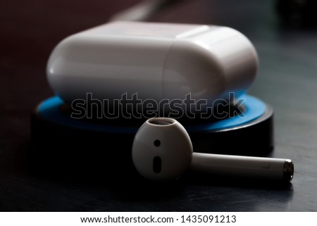 Airpod with charging case on a wireless charger in low key lighting Royalty-Free Stock Photo #1435091213
