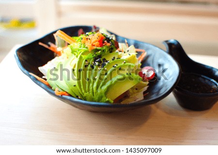Healthy organic Japanese style, salad with avocado, super food, high omega, probiotics, delicious with soy dressing in black bowl on light wooden table in Japanese food restaurant background