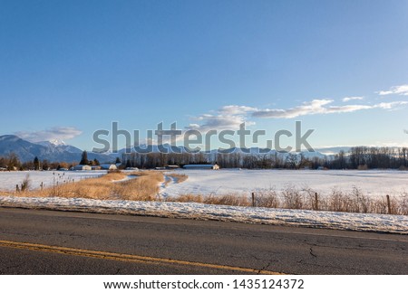 Beautiful winter landscape, snowy mountains around Kilby Park, British Columbia, Canada. Snow in the foreground on the fields as well. Pine trees are visible on the mountain, it is not covered by snow