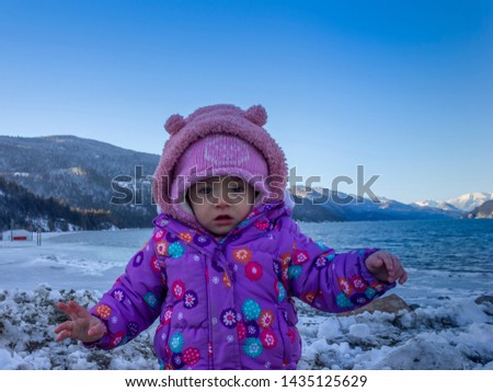 20 months old baby enjoying the nice weather outside. Toddler girl portraits in natural light. Little girl pictures in nature, in Winter. Snow in back. Harrison Hot Springs, British Columbia, Canada