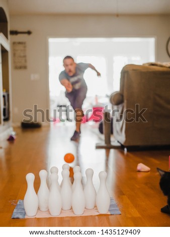 Guy bowling at home in the living room with toy bowling set