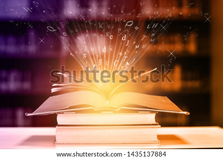 Open book on the table and English alphabet Floating above the book in the library and blur bookshelf background.