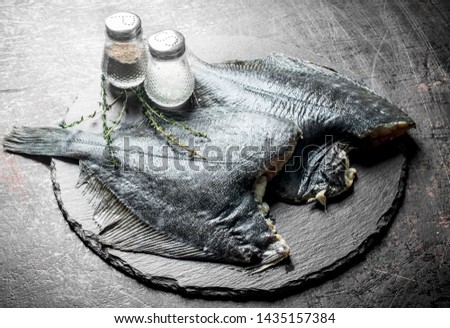 Raw fish on stone Board with spices and thyme. On dark rustic background