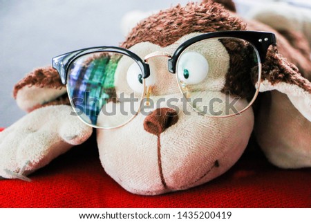 Monkey doll wearing glasses on red pillow