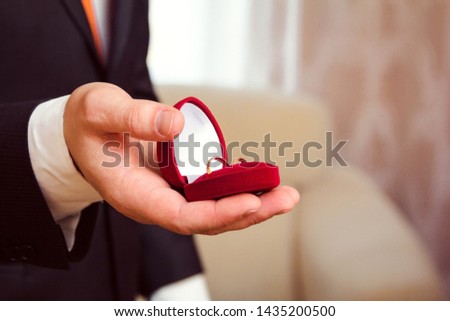 wedding rings in a box in the groom's hand close