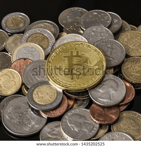 Golden bitcoin over a pile of various coins.