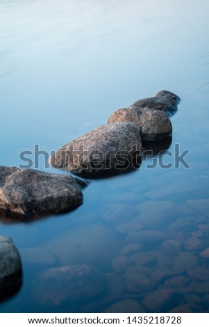 Long exposure of stones at lake Saimaa in Finland. Water is transparent and stones in bottom of the water are visible.