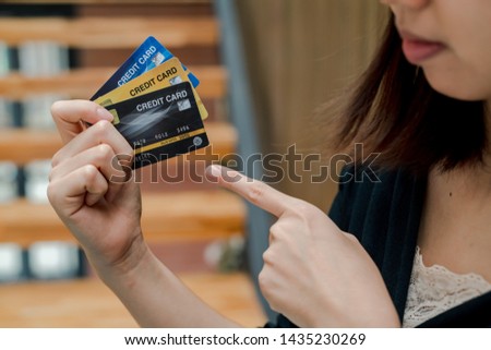 Closeup Asian beautiful woman Wearing a black shirt Sitting in the stairs in the house Have a credit card in hand Is buying online products with a laptop computer.