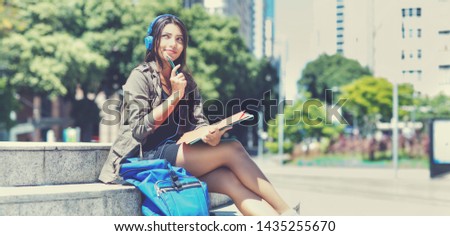 Beautiful latin american female student with headphone in city in the summer