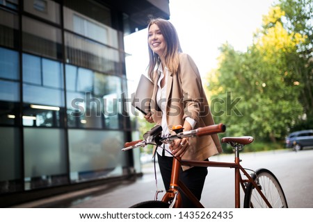 Young businesswoman standing on a city street with bicycle