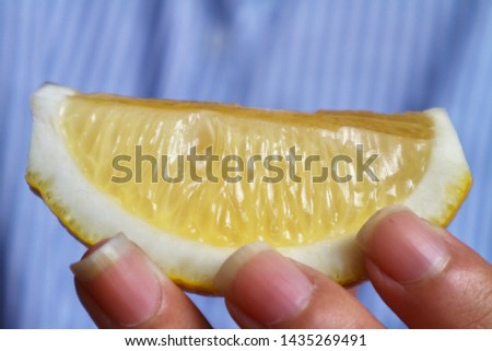 Hand hold fresh slice lemon in blurred blue background