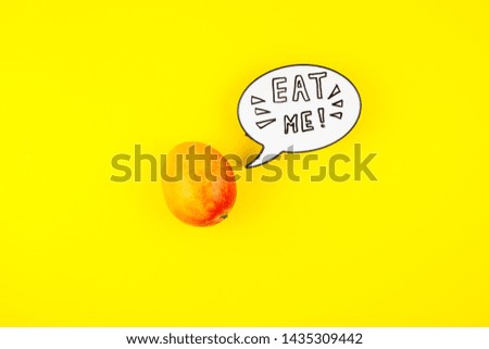 Mango fruit in creative conceptual top view flat lay composition with lightbox bubble with Eat me handwritten slogan isolated on bold color background in minimal style with copy space. Pop art poster