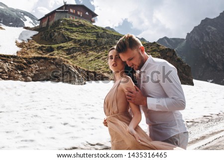 Beautiful bride in a dress  and the groom stand in the mountains on the rocks.