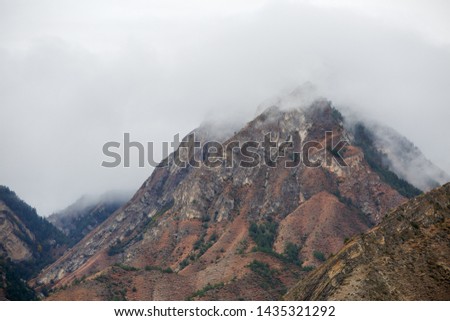 Picture of mountains with green vegetation, smoke above tops