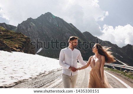 attractive young wedding couple walking at the long road in mountains