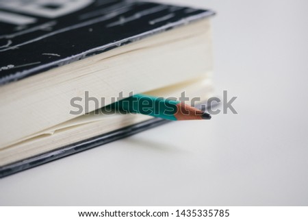 The pencil emerges from the skating book. Placed on a white table , Closeup