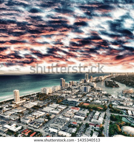Aerial view of Miami Beach at sunset from helicopter. City skyline and water. Cloudy skies, a vacation dream.
