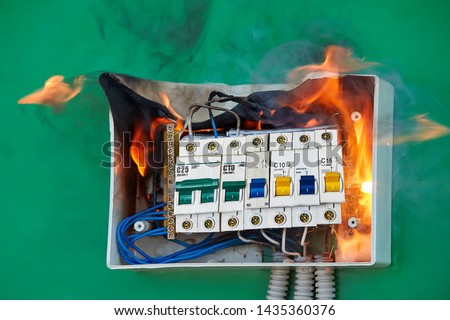 Electrical faults of circuit breakers become the cause of fire. Loose wires caused fire inside electrical fuse box. Bad electrical switchboard caused fire inside apartment. Royalty-Free Stock Photo #1435360376