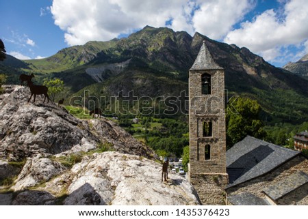Ancient church in Boi village, Catalonia, Spain. Historical roman building in pyrenees mountains. Brick walls of the church tower, Spanish countryside. Green hills and peaks on the background