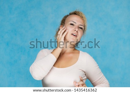Photo portrait of a beautiful girl blonde woman with short curly hair on a blue background talking and showing a lot of emotions. An experienced model shows hands. Beauty. Made in studio
