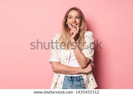 Portrait of a smiing pensive beautiful young blonde woman standing isolated over pink background, looking away Royalty-Free Stock Photo #1435431512